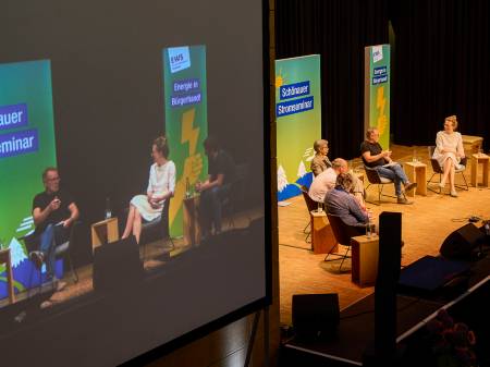 Blick von der Empore auf die Bühne, auf der eine Diskussion stattfindet.