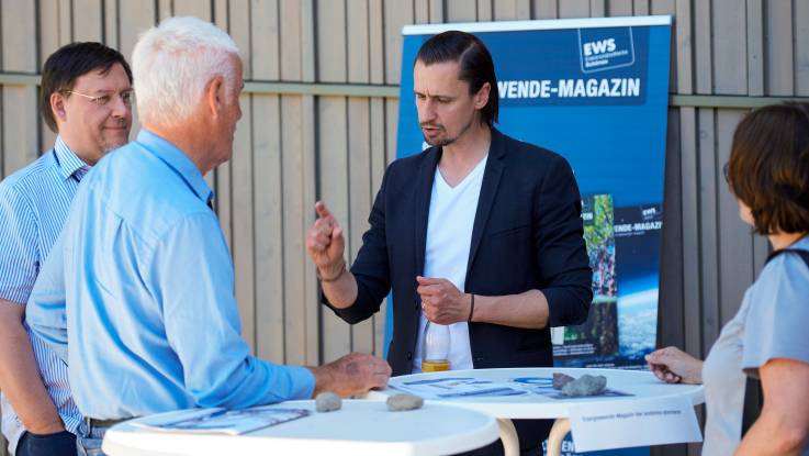 Peter Ugolini-Schmidt spricht im Hof am Stand der EWS  mit Seminarteilnehmern.