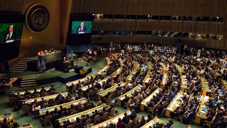 Blick in einen Versammlungssaal erhabener Größe und Ausstattung, mit zahlreichen vollbesetzten Sitzreihen, ausgerichtet auf ein Podium. 