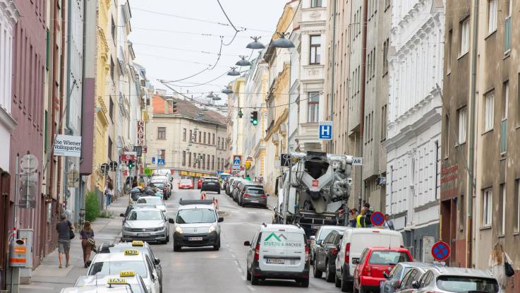 Eine dicht bebaute Straße voller Pkw: Auf den schmalen Gehwegen und an den Hausfassaden fehlt jegliche Begrünung.