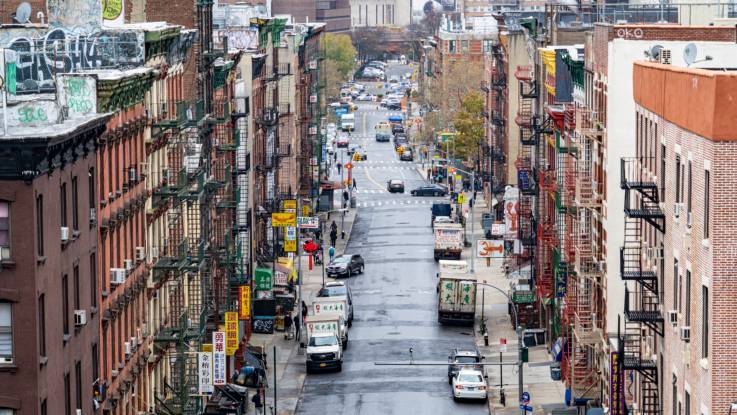 Eine Häuserflucht in New York: an den teils baufälligen Fassaden hängen Feuerleitern und chinesische Leuchtreklamen.