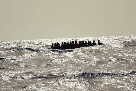 Auf offener See sind mindestens 20 Menschen zu sehen, die offenbar in einem sehr kleinen Boot sitzen.