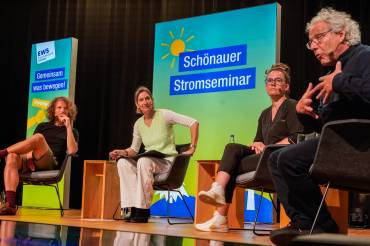 Vier Personen der Diskussionsrunde sitzen im Halbkreis auf der Bühne.