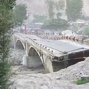 Ein qualitativ schlechtes TV-Bild zeigt eine kollabierende Brücke in einem Unwetter.