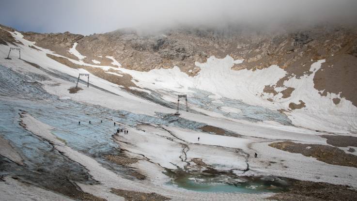 Die Oberfläche eines Gebirgshangs bildet ein Mosaik aus Schnee, Eisresten und kargem Geröll. 