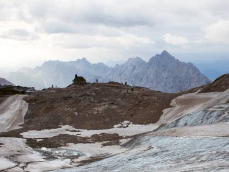 Vor der Kulisse zerklüfteter Alpengipfel steht eine kleine Kapelle – um sie herum befindet sich das Eis auf dem Rückzug. 