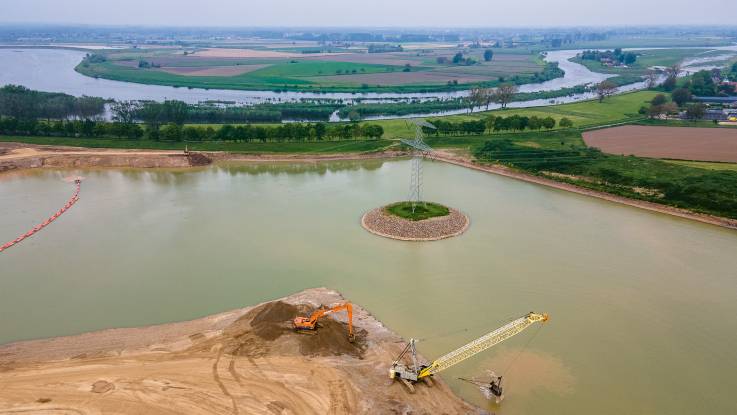 Weitere Ansicht des Kieshafens von oben: Auf einer künstlichen Insel ein Strommast, weiter hinten eine Flussschleife.