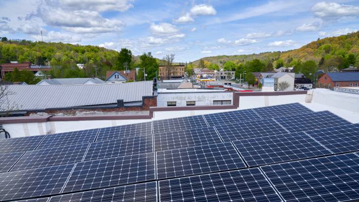 Auf einem leicht abschüssigen Flachdach sind PV-Module dicht auf Stoß installiert.