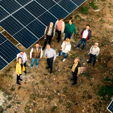 Zwei junge Männer posieren symphatisch lächelnd neben Photovoltaikmodulen auf einem Dach in Lissabon.