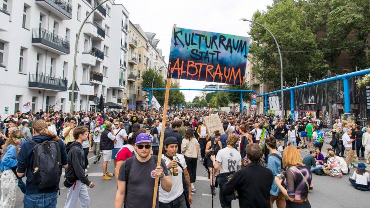 Auf einer Straße haben sich tausende Menschen zum Protest versammelt,  auf einem Plakat steht: Kulturraum statt Albtraum. 