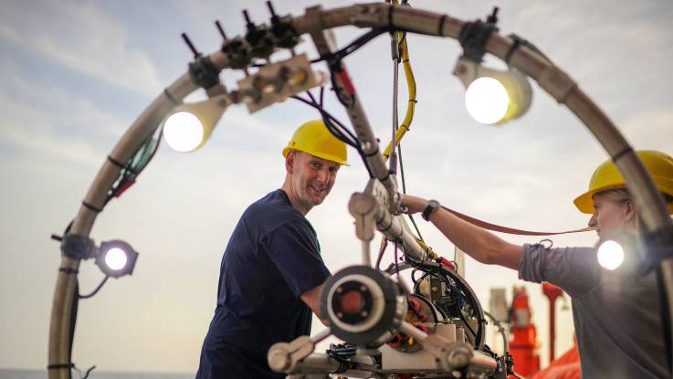  Über Wasser: Ein Mann und eine Frau arbeiten an einer technischen Apparatur, an der helle Lampen installiert sind.