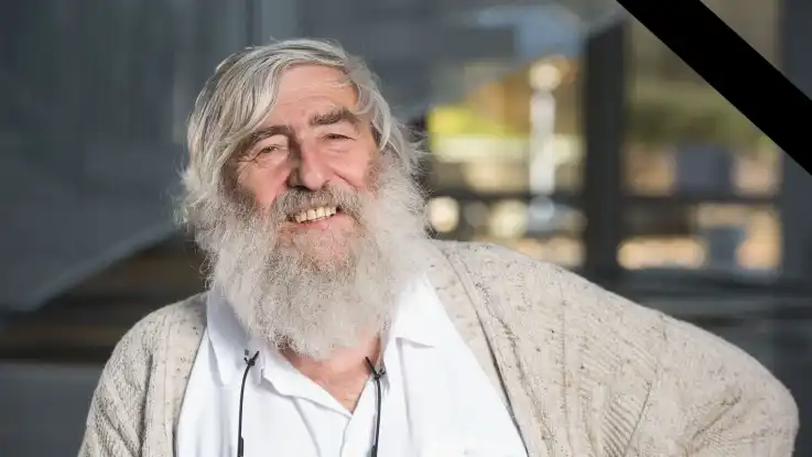 Michael Sladek, mit weißem Haar und langem weißen Bart, schaut mit warmherzigem Blick in die Kamera. Am oberen Bildrand findet sich ein Trauerband.