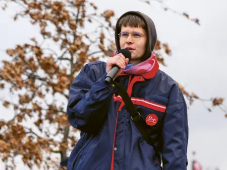 Jakob Springfeld, mit Hoodie und Regenjacke, hält ein Mikrofon und spricht.