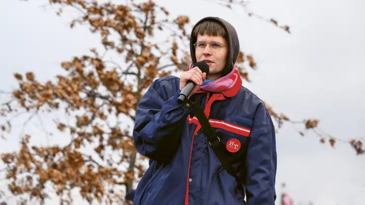 Jakob Springfeld, mit Hoodie und Regenjacke, hält ein Mikrofon und spricht. 