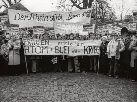 Eine Schwarz-Weiß-Aufnahme zeigt Demonstrantinnen und Demonstranten aller Altersklassen mit zahlreichen Bannern und Schildern.